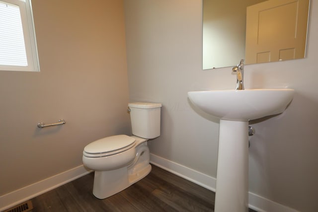 bathroom featuring toilet, visible vents, baseboards, and wood finished floors