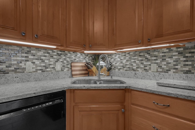 kitchen with light stone countertops, black dishwasher, sink, and backsplash