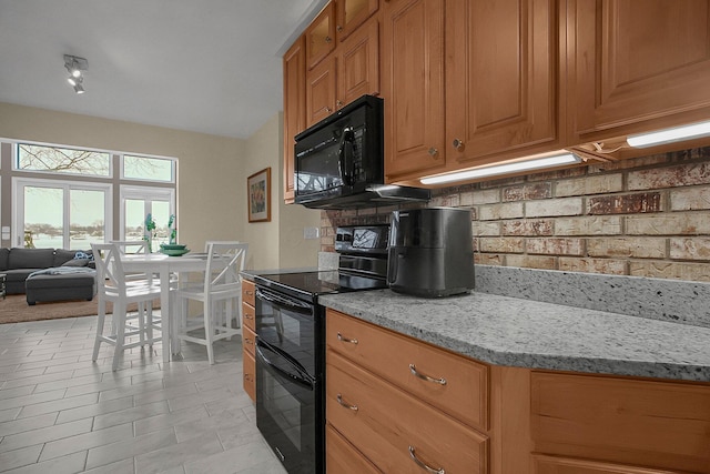 kitchen with tasteful backsplash, light tile patterned floors, light stone counters, and black appliances