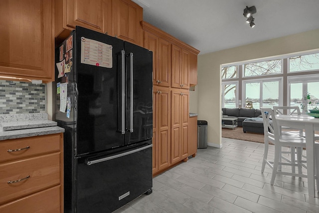 kitchen featuring black refrigerator, light tile patterned floors, decorative backsplash, and light stone countertops