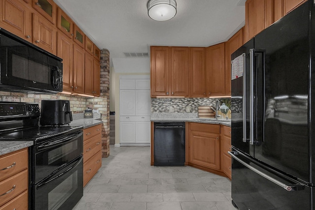 kitchen with sink, decorative backsplash, light stone counters, and black appliances