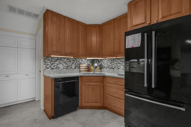 kitchen with backsplash, sink, light stone counters, and black appliances