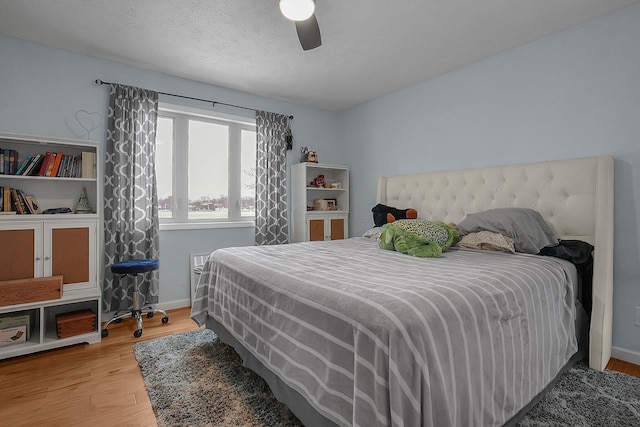 bedroom featuring hardwood / wood-style flooring, a textured ceiling, and ceiling fan