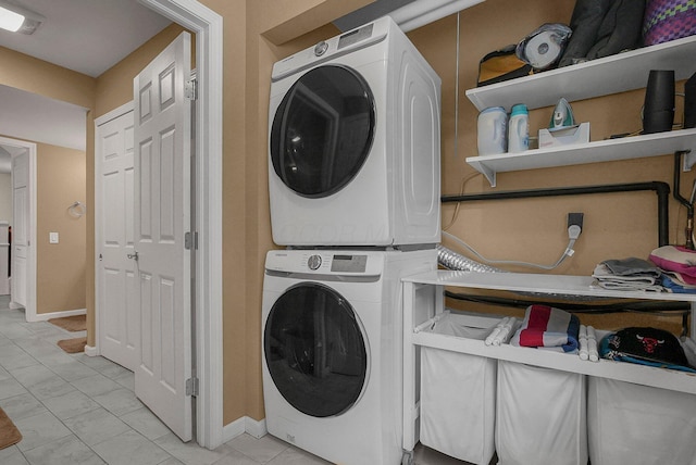 washroom with light tile patterned flooring and stacked washer / drying machine