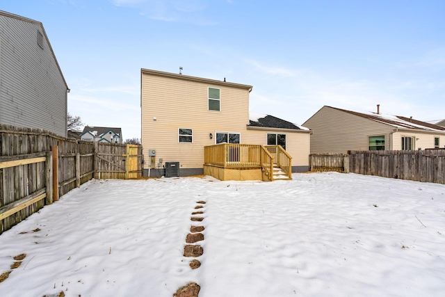 snow covered rear of property with central AC unit and a deck