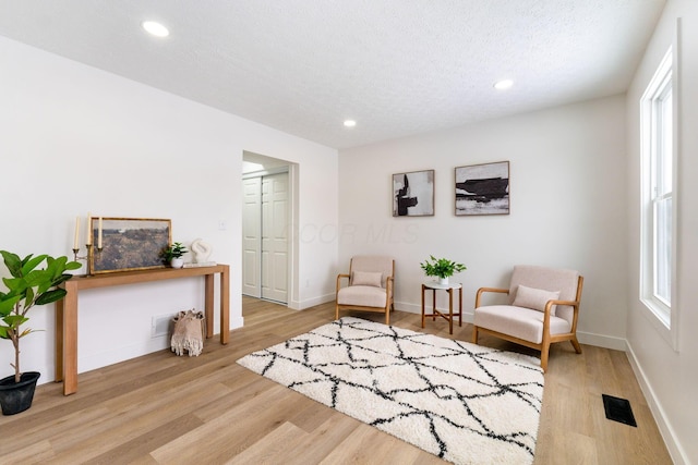 living area featuring a textured ceiling and light hardwood / wood-style floors