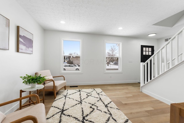 living area featuring a textured ceiling and light hardwood / wood-style floors