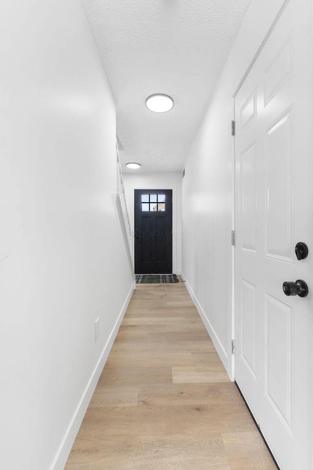 doorway to outside featuring a textured ceiling and light hardwood / wood-style floors