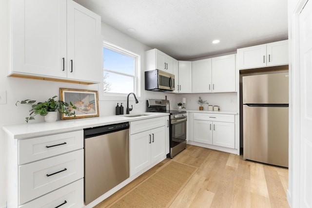 kitchen featuring white cabinets, appliances with stainless steel finishes, sink, and light hardwood / wood-style flooring