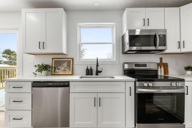 kitchen featuring a wealth of natural light, appliances with stainless steel finishes, white cabinetry, and sink