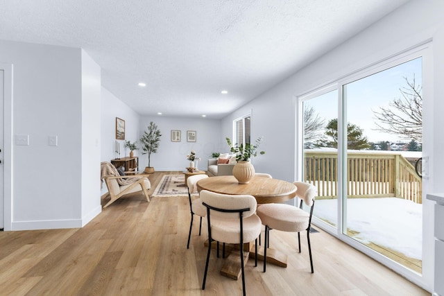 dining space with a textured ceiling and light hardwood / wood-style flooring