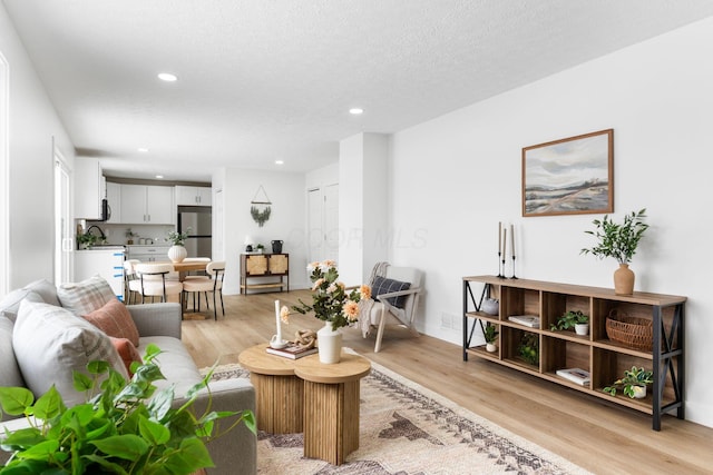 living room featuring light wood-type flooring and a textured ceiling