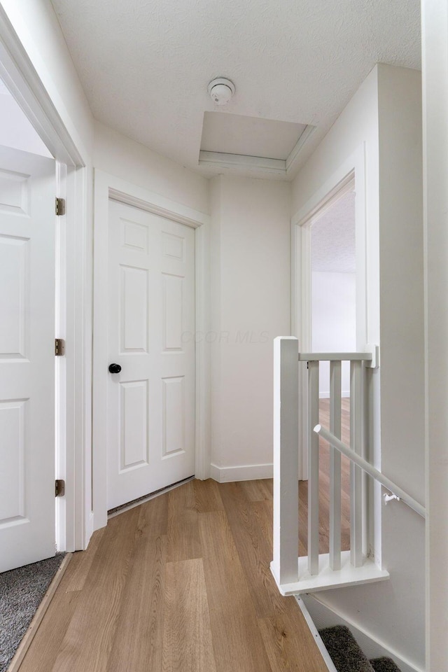 hall with a textured ceiling and light hardwood / wood-style floors