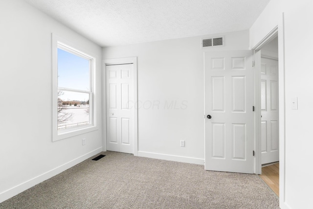 unfurnished bedroom with carpet floors, a textured ceiling, and a closet