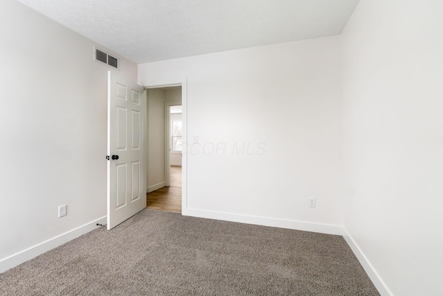 spare room with a textured ceiling and carpet flooring