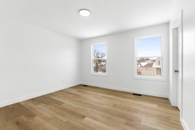 empty room featuring a textured ceiling and light hardwood / wood-style flooring