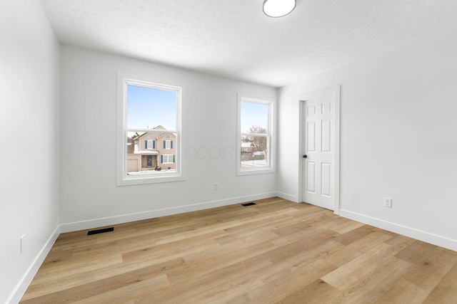 unfurnished room featuring a textured ceiling and light hardwood / wood-style flooring