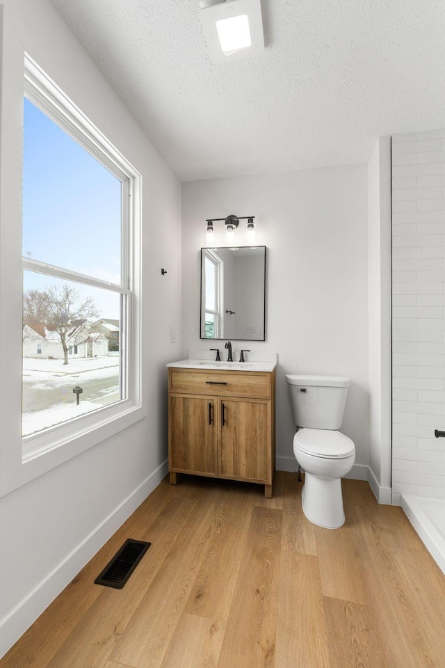 bathroom featuring toilet, vanity, a textured ceiling, and hardwood / wood-style floors