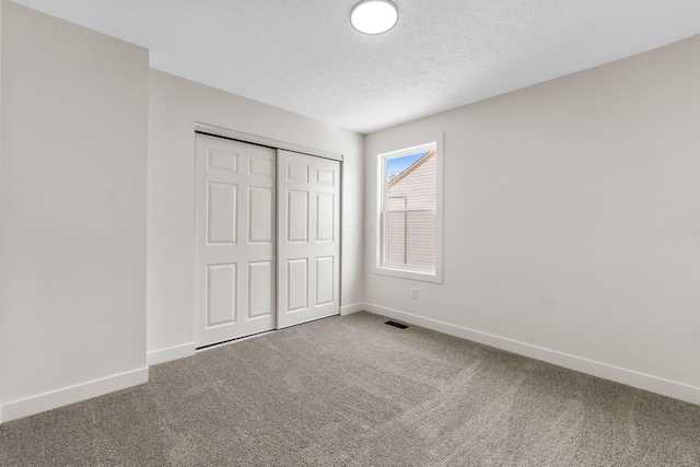 unfurnished bedroom with carpet, a closet, and a textured ceiling