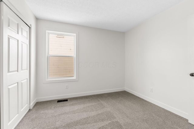 carpeted spare room with a textured ceiling