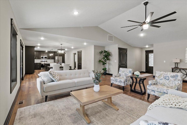 living room with vaulted ceiling, dark hardwood / wood-style floors, and ceiling fan with notable chandelier