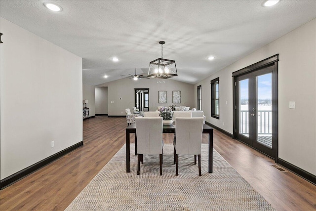 dining space featuring vaulted ceiling, ceiling fan with notable chandelier, a textured ceiling, and hardwood / wood-style floors