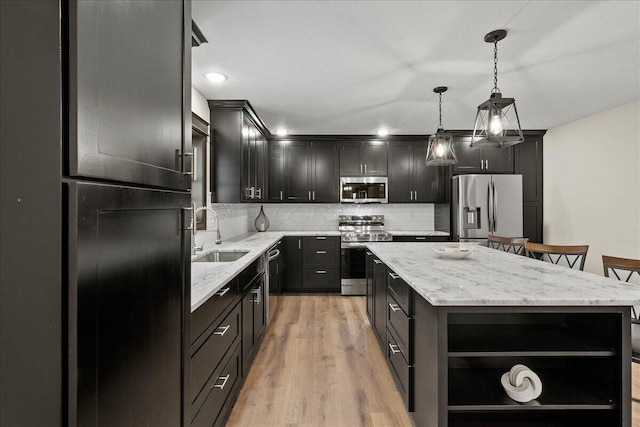 kitchen with appliances with stainless steel finishes, decorative light fixtures, a kitchen island, and sink