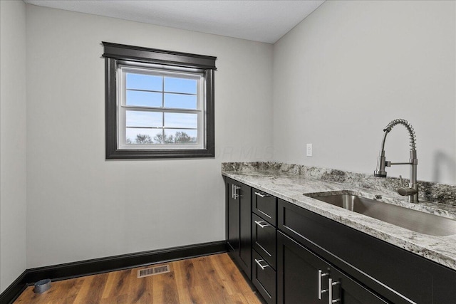 interior space with light stone counters, sink, and hardwood / wood-style floors