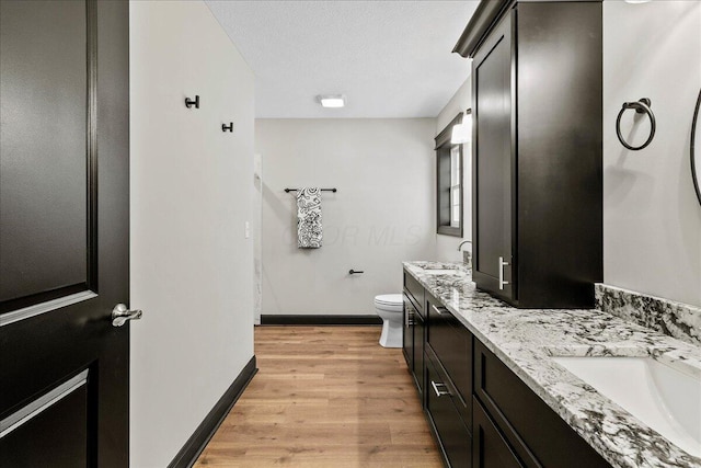 bathroom featuring toilet, a textured ceiling, hardwood / wood-style floors, and vanity