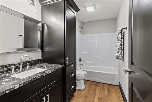 full bathroom with toilet, hardwood / wood-style flooring, shower / bathing tub combination, a textured ceiling, and vanity