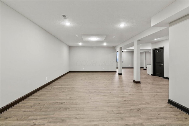 basement featuring light hardwood / wood-style floors and a textured ceiling