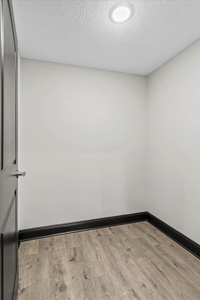 empty room with a textured ceiling and light wood-type flooring