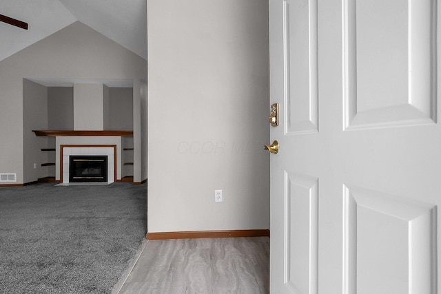 unfurnished living room featuring lofted ceiling, light carpet, and a fireplace