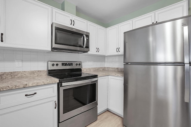 kitchen featuring backsplash, white cabinetry, stainless steel appliances, and light countertops