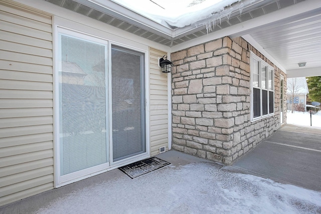 entrance to property featuring a porch and stone siding