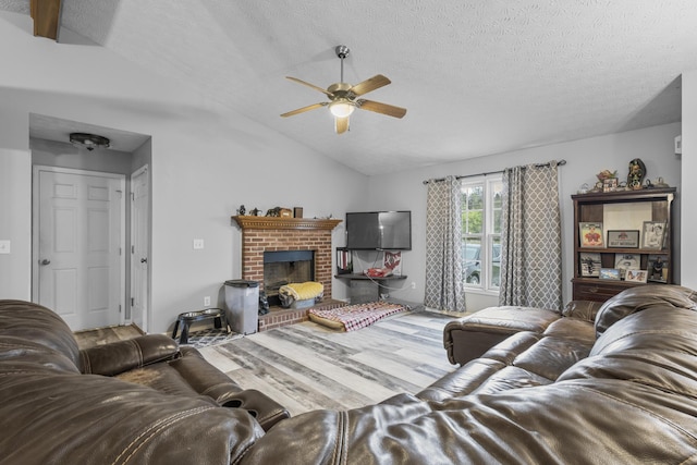 living room featuring ceiling fan, vaulted ceiling, a fireplace, hardwood / wood-style floors, and a textured ceiling