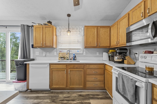 kitchen featuring sink, white appliances, a textured ceiling, and pendant lighting