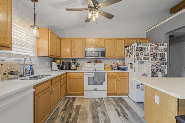 kitchen with white appliances, a textured ceiling, vaulted ceiling, pendant lighting, and sink