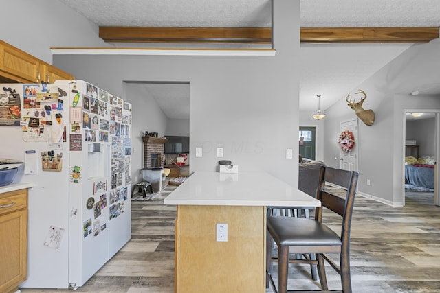 kitchen with white fridge with ice dispenser, beamed ceiling, dark hardwood / wood-style floors, kitchen peninsula, and a breakfast bar