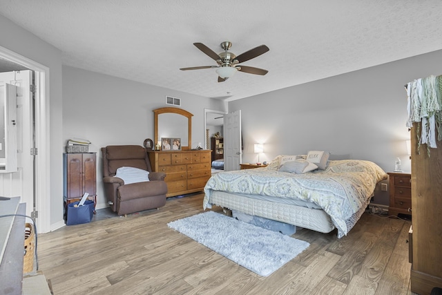 bedroom featuring ceiling fan, light wood-type flooring, and a textured ceiling