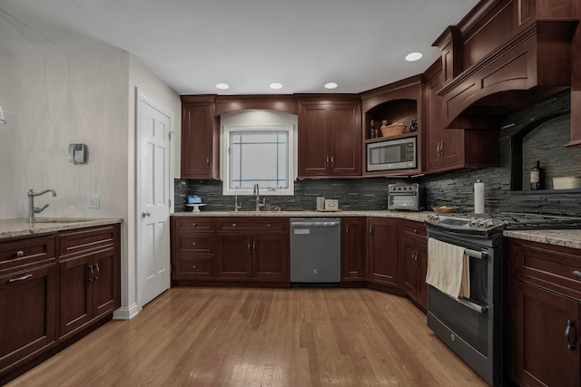 kitchen featuring premium range hood, appliances with stainless steel finishes, light stone counters, and sink