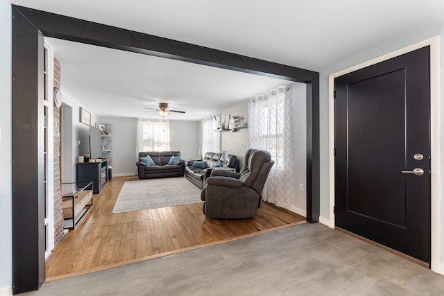 living room with ceiling fan, light hardwood / wood-style flooring, and beamed ceiling