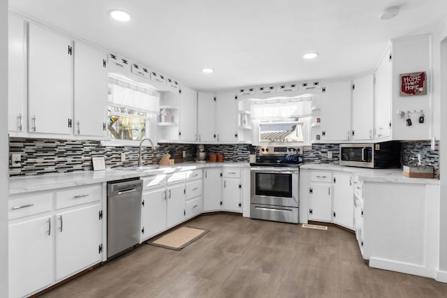 kitchen with a wealth of natural light, appliances with stainless steel finishes, white cabinets, and sink