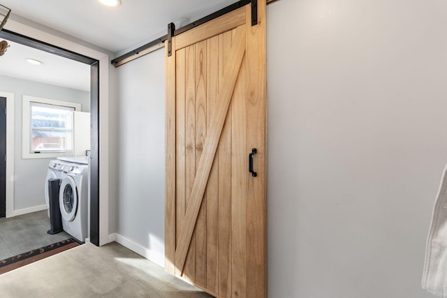 laundry room with separate washer and dryer and a barn door