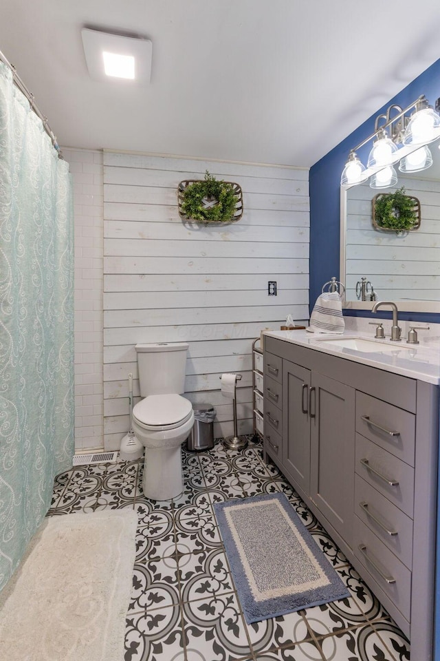 bathroom featuring toilet, vanity, wooden walls, and a shower with shower curtain