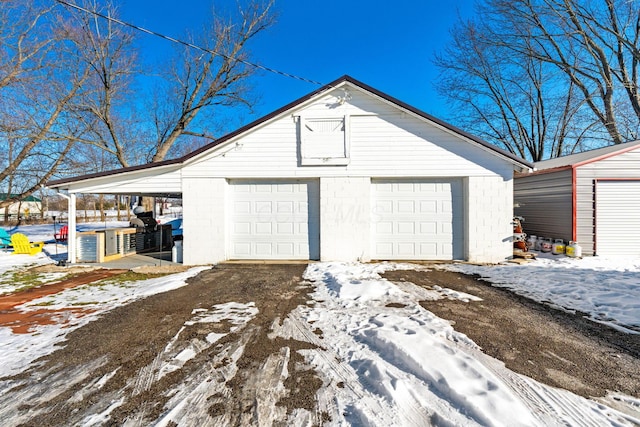 snow covered garage with a carport