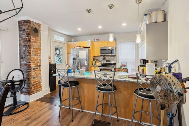 kitchen with appliances with stainless steel finishes, dark hardwood / wood-style flooring, backsplash, kitchen peninsula, and stone counters