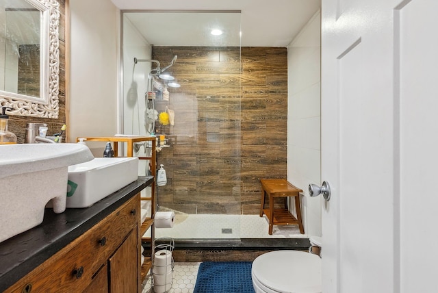 bathroom with toilet, tile patterned floors, tiled shower, and vanity