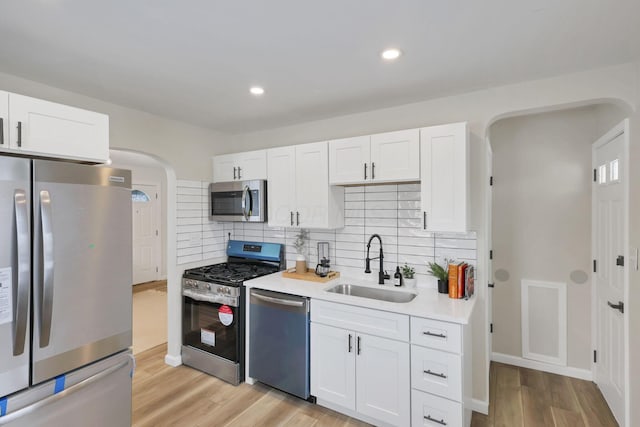 kitchen featuring sink, white cabinets, stainless steel appliances, and tasteful backsplash