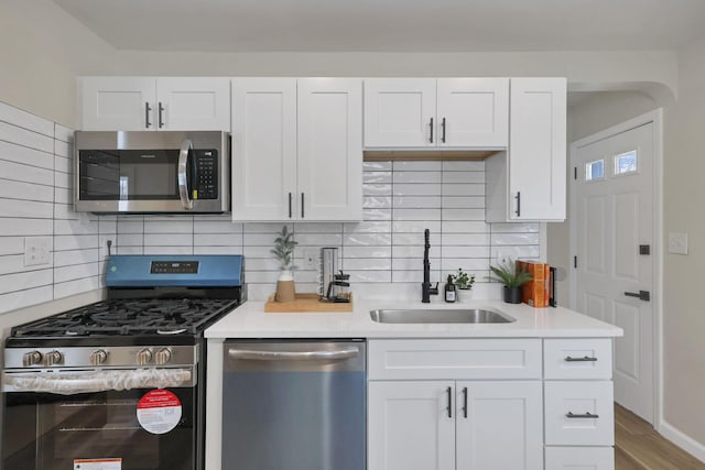 kitchen featuring appliances with stainless steel finishes, backsplash, white cabinetry, and sink